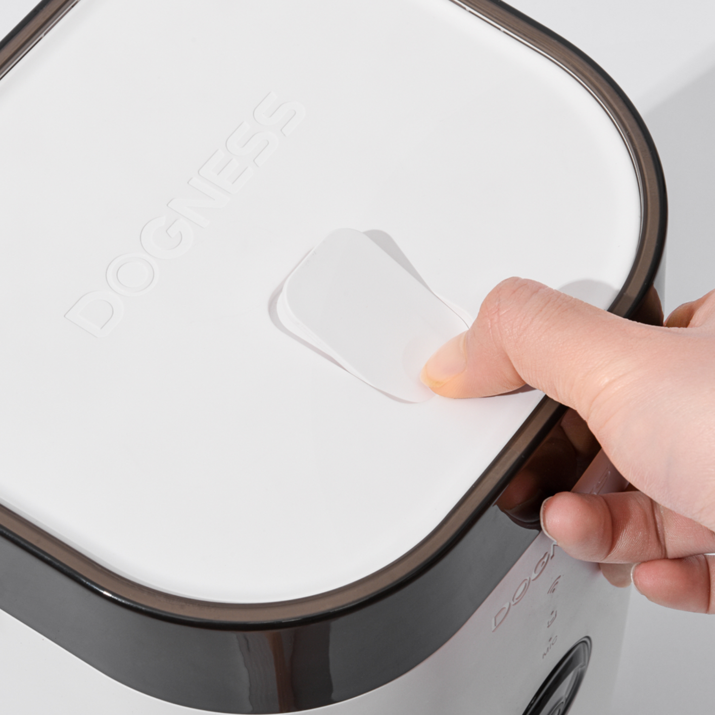 Hand opening a white lid with a black rim on a white background