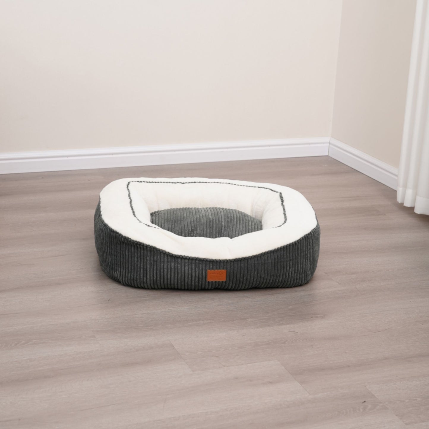 Dog bed with a white cushion on a wooden floor