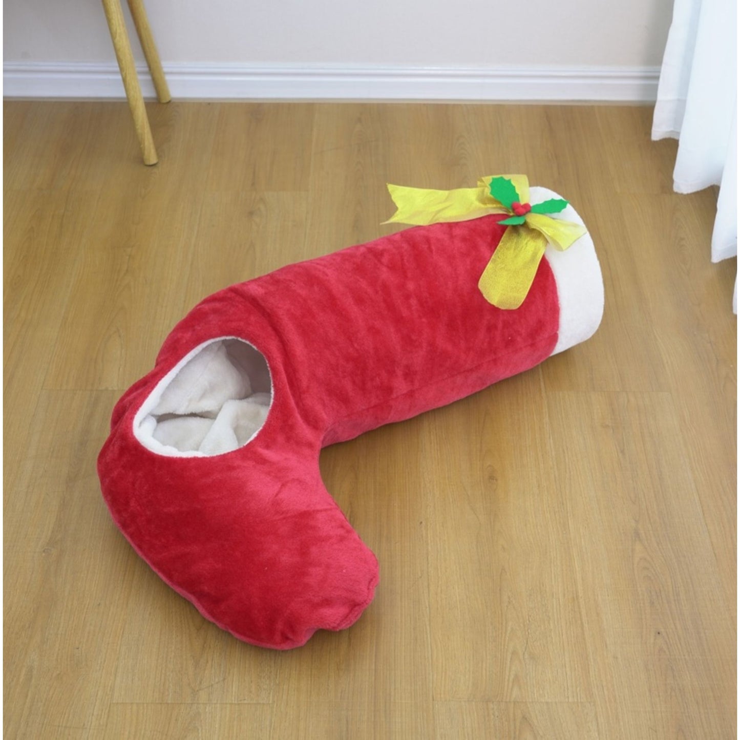 Red U-shaped cushion with a green bow on a wooden floor