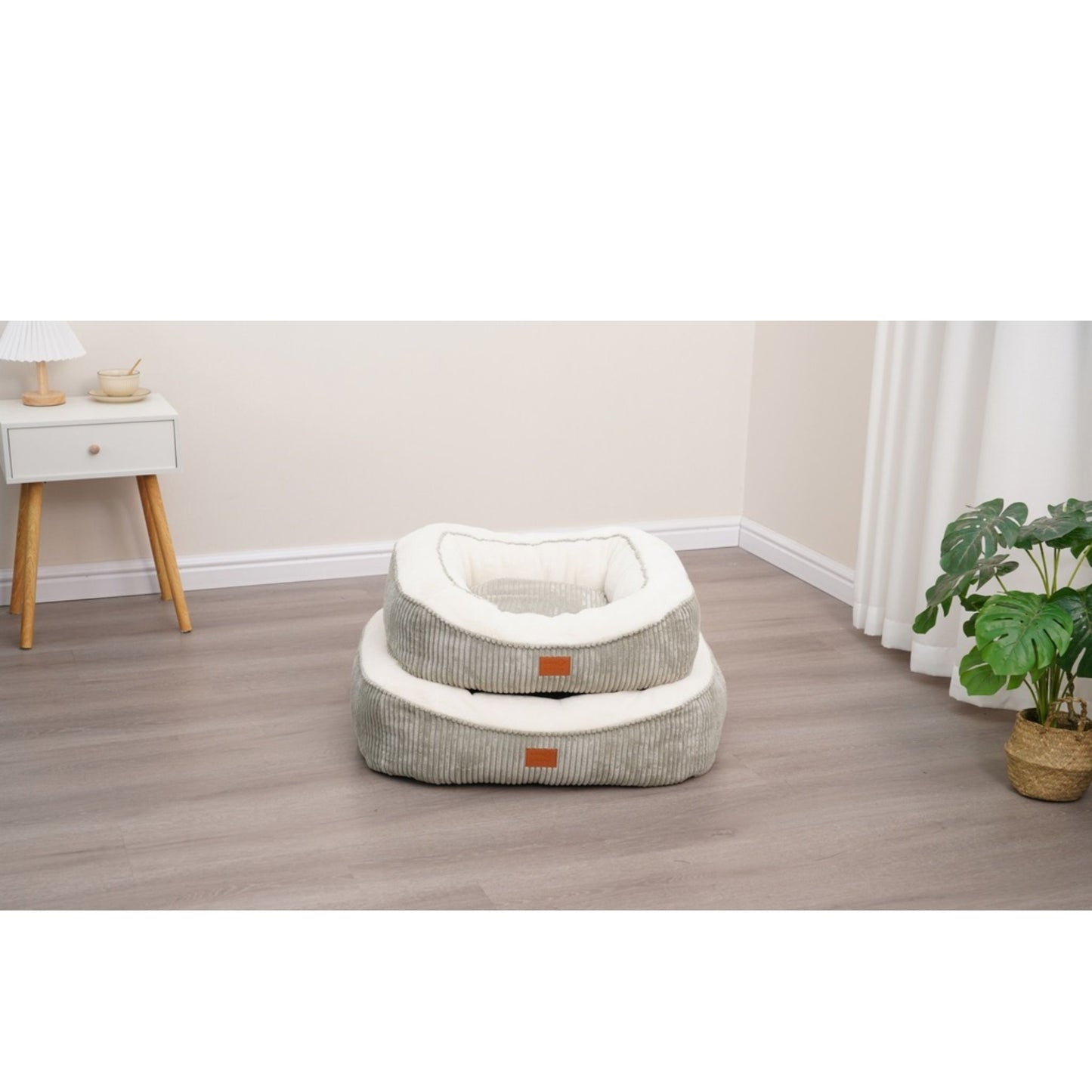 Pet bed with a striped pattern in a room with a white wall, wooden floor, and a plant.