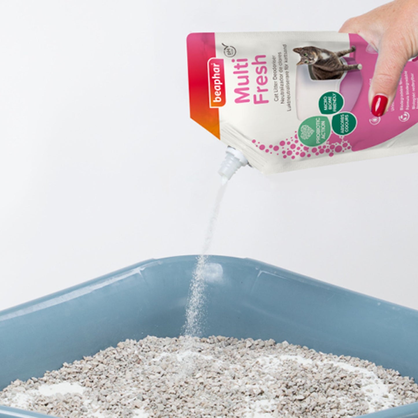 Person pouring Bephar Multi Fresh cat litter into a blue litter box.