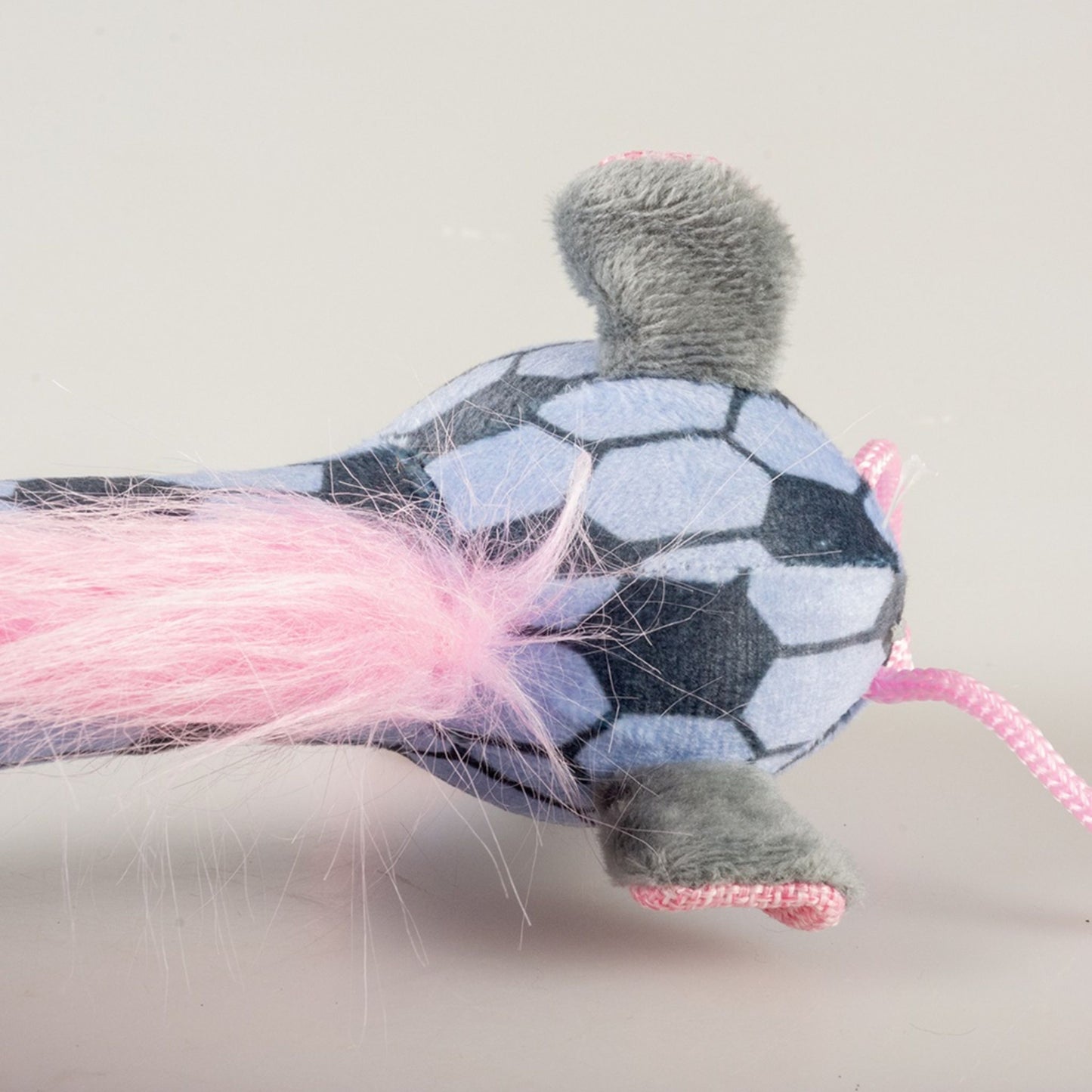 Toy resembling a soccer ball with pink feather attachment on a light grey background