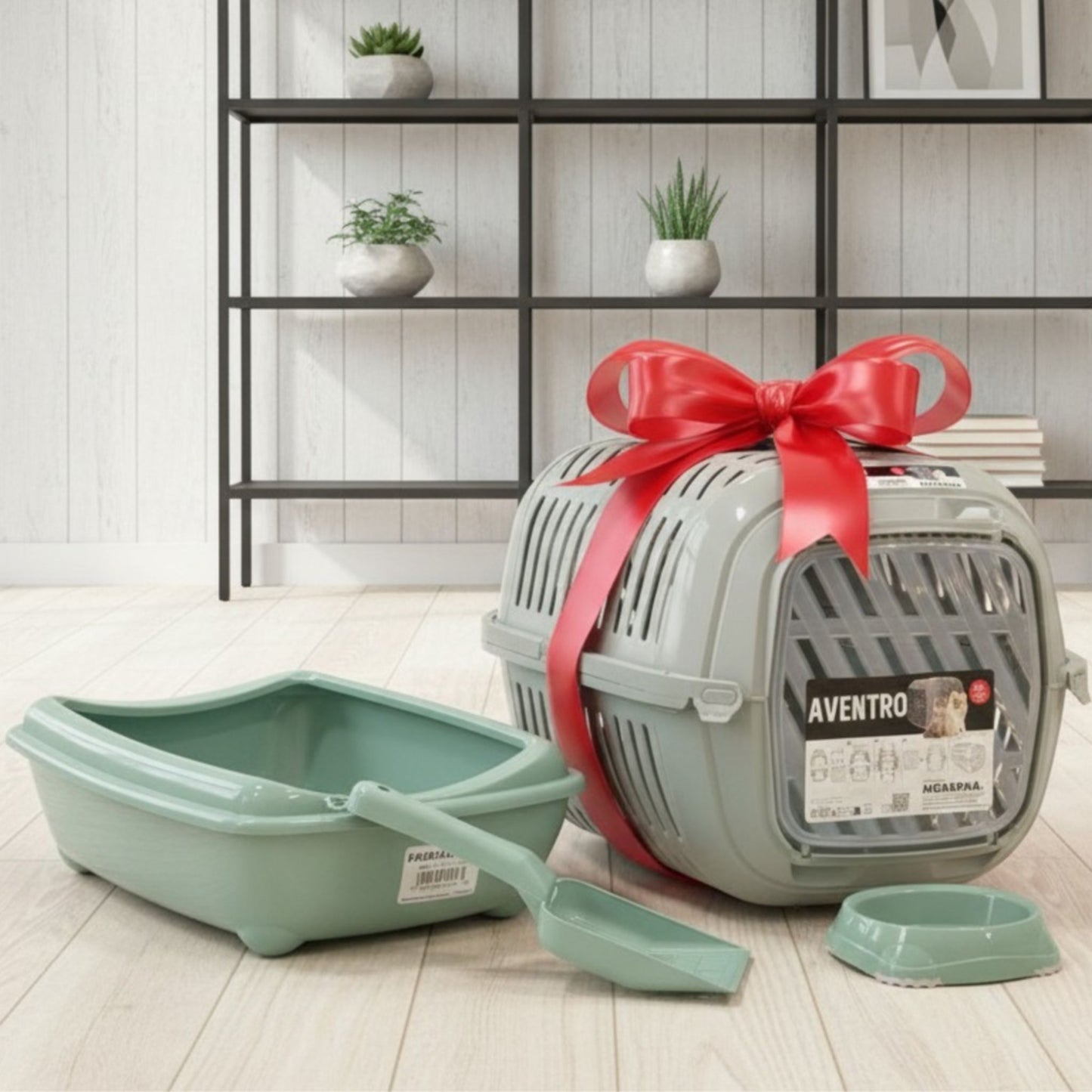 Cat litter box, scoop, and carrier with a red bow on a light wooden floor.