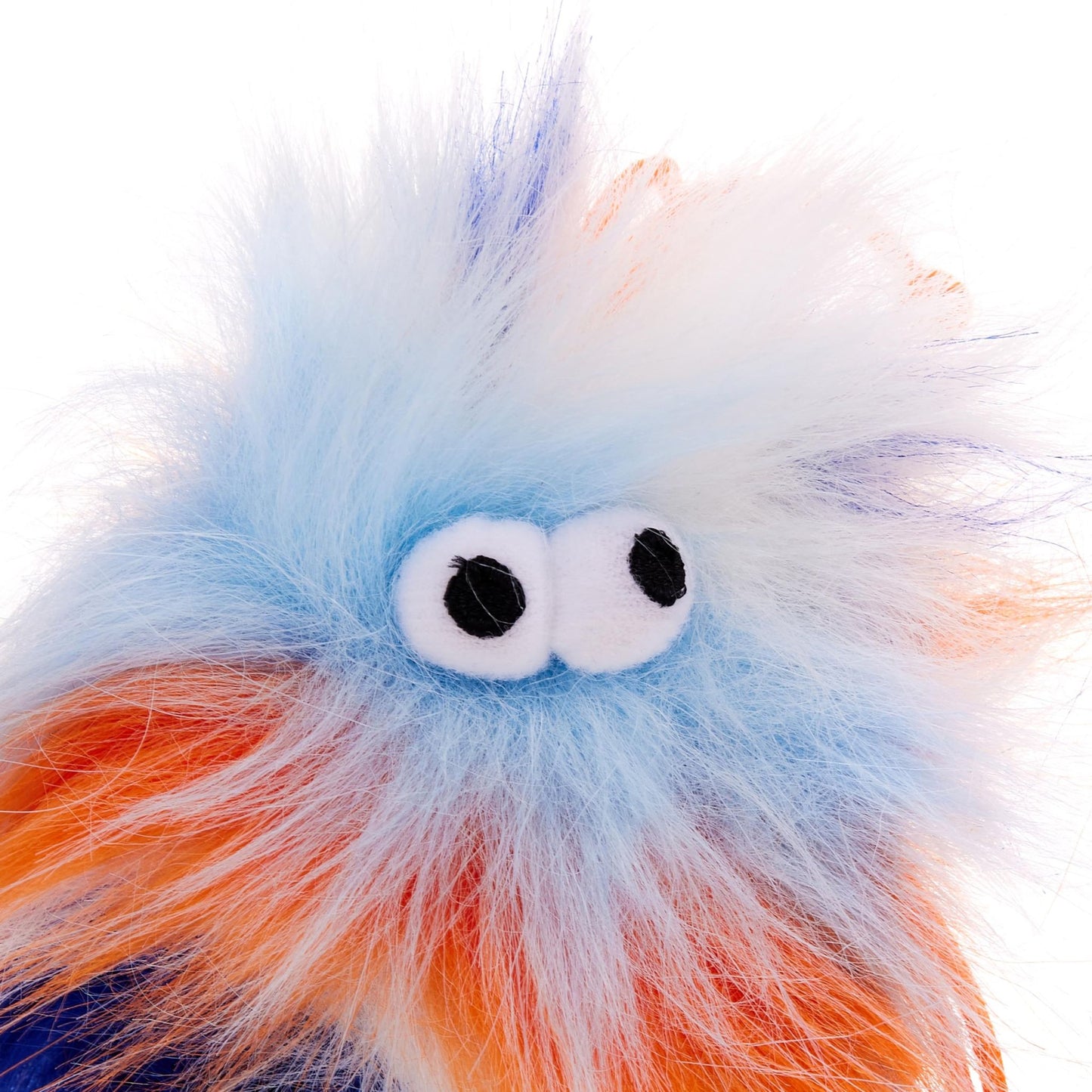 Close-up of a colorful, fluffy toy with googly eyes on a white background