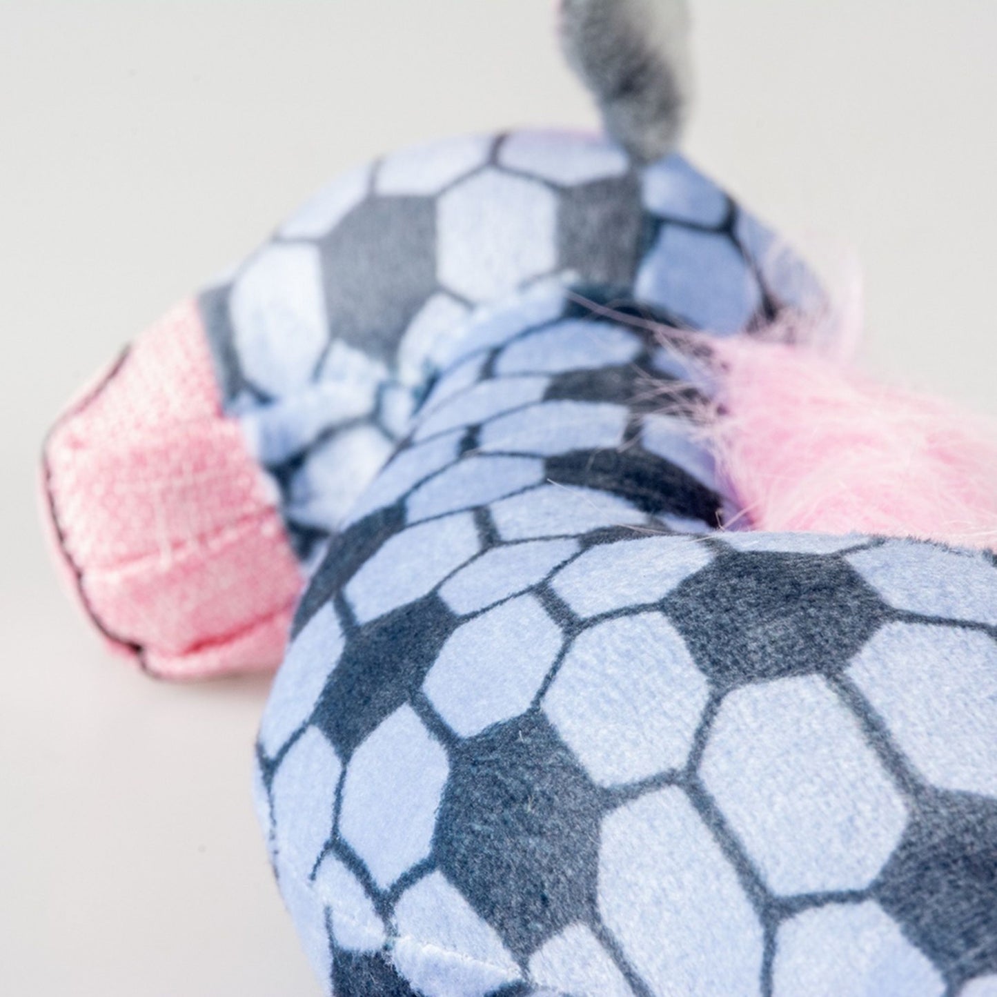 Close-up of a plush toy with pink and grey geometric pattern